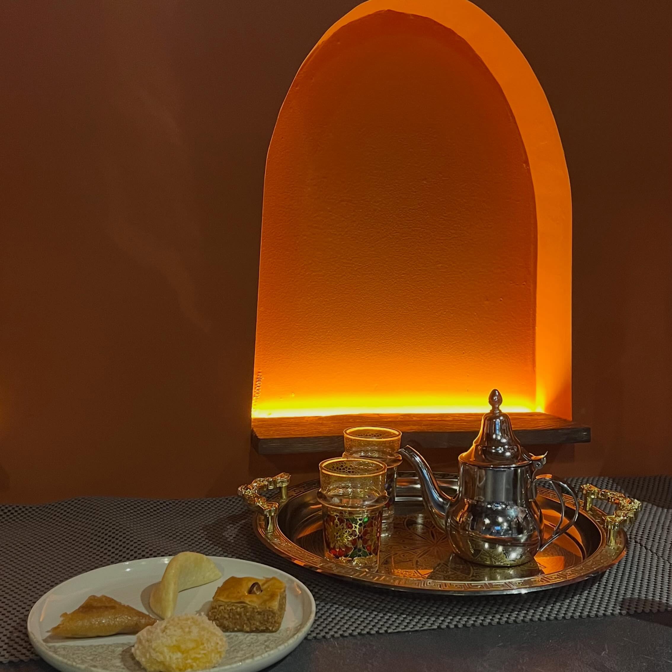 Plateau de thé marocain et pâtisseries dans une niche lumineuse